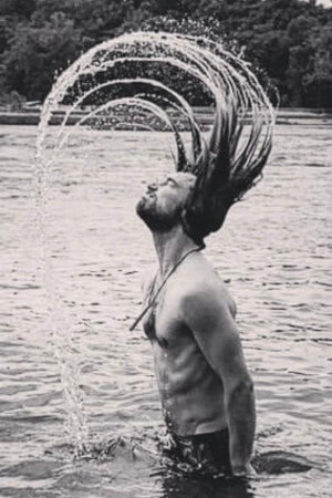nude life drawing model waist deep in a lake flicking his wet hair near glendene