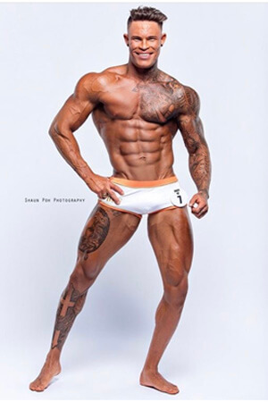 tanned, muscular and super ripped dark haired life drawing model posing in small trunks