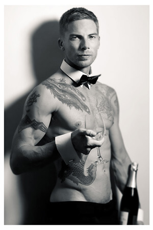 sultry looking shirtless waiter offering champagne wearing bow tie, collar and cuffs in auckland's three kings