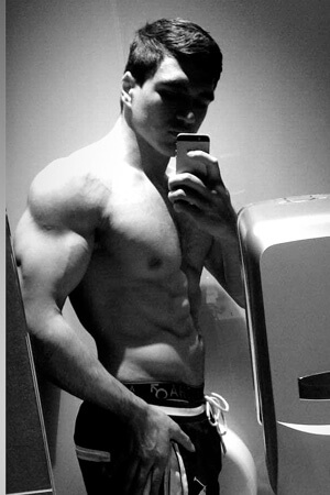 super buff topless butler posing for a side pose selfie in auckland's mairangi bay