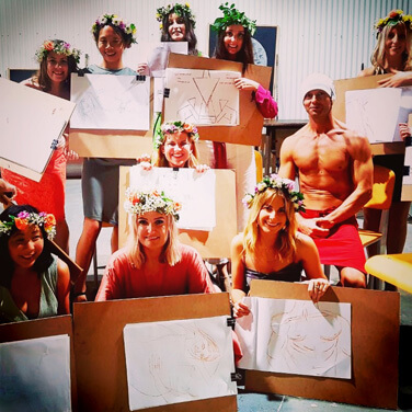 Hens wearing flower crowns showing off their sketches from a life drawing class