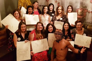Hens party group holding up their sketches from a life drawing class